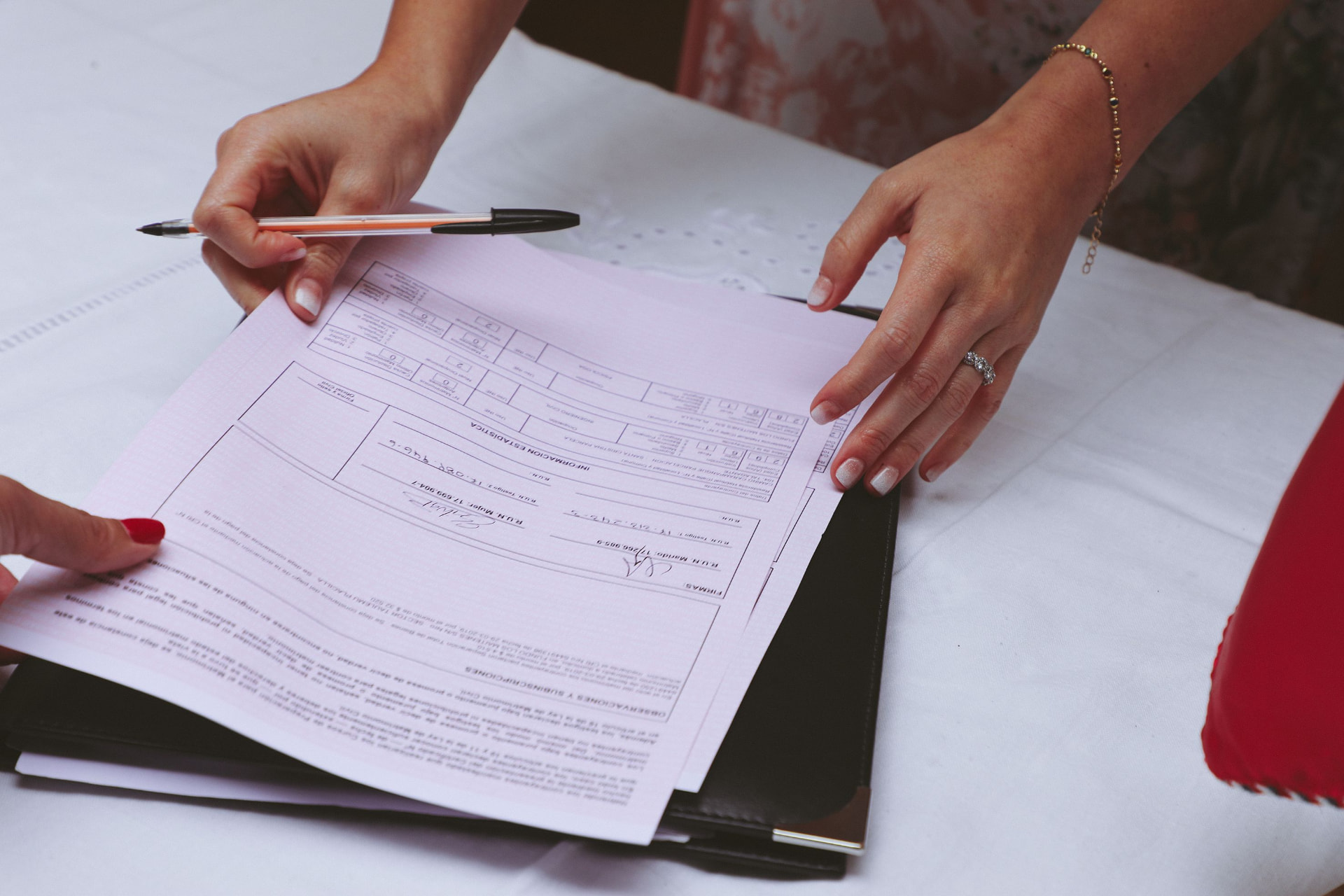 Hands reviewing Spanish utility paperwork and household documents at a table